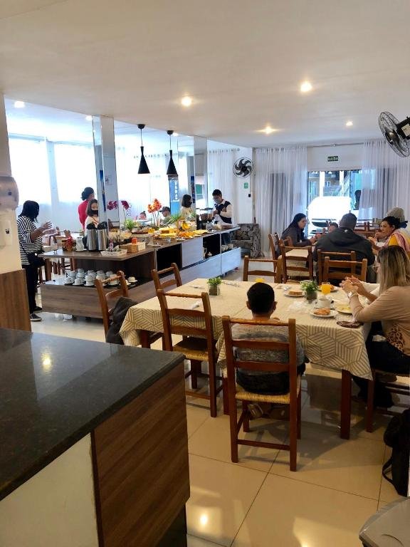 Salão de café da manhã do Hotel Lorimar com hóspedes nas mesas e buffet ao fundo