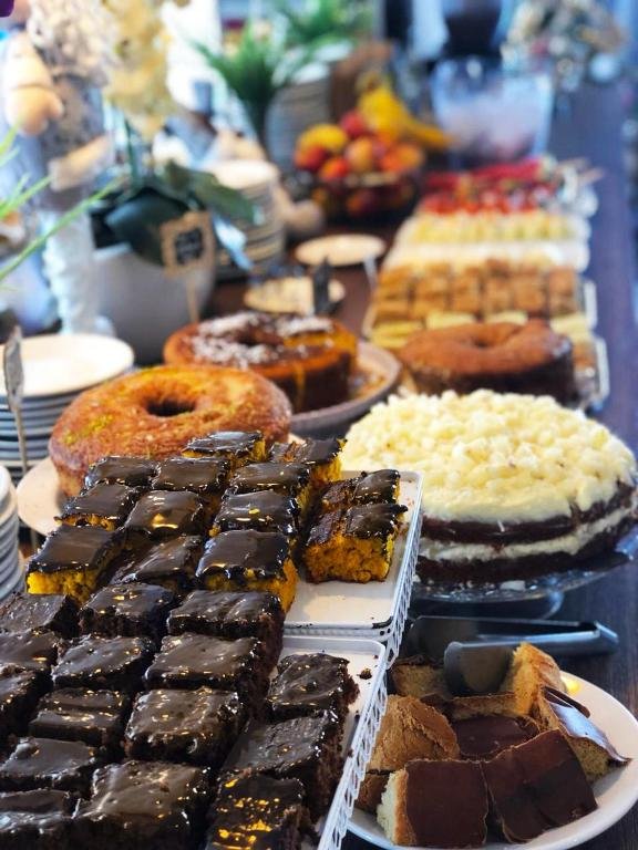 Grande variedade de bolos e roscas dispostos ao longo da mesa do café da manhã