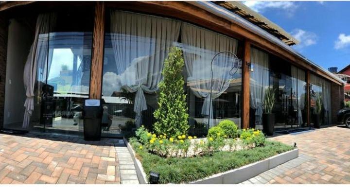 Entrada do Hotel Lorimar com canteiro central de jardim e amplas vidraças