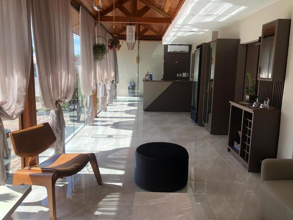 Hall e recepção do Hotel Lorimar, com piso polido, teto de madeira e cortinas claras